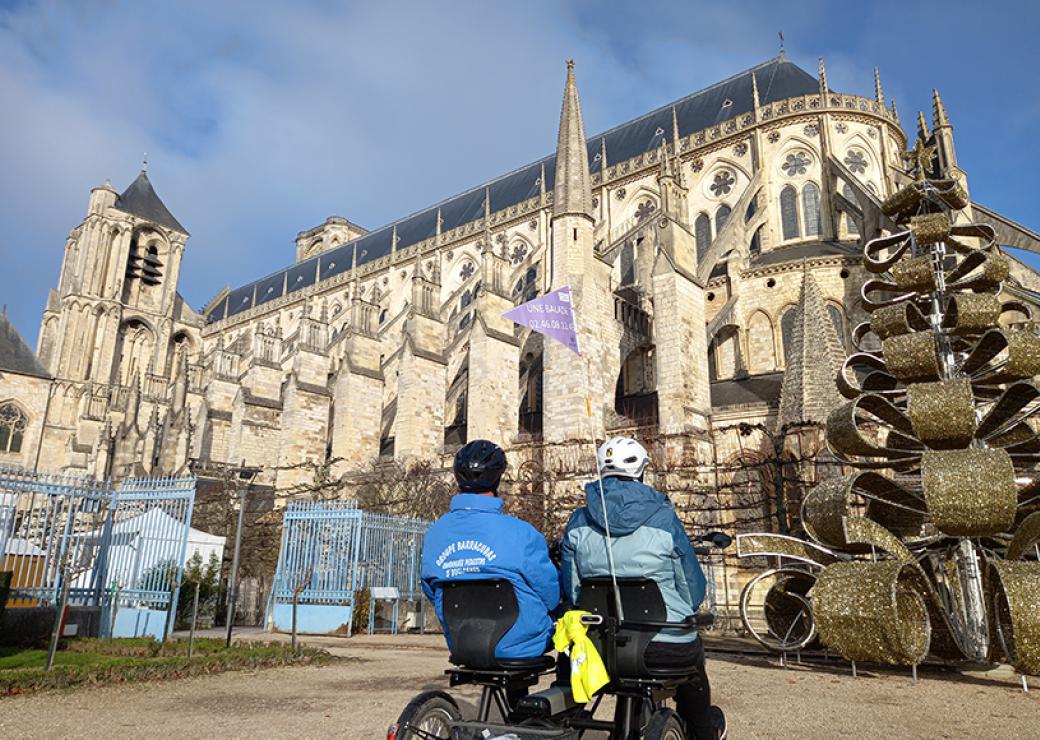 Des personnes installées sur un vélo deux place regardent une cathédrale