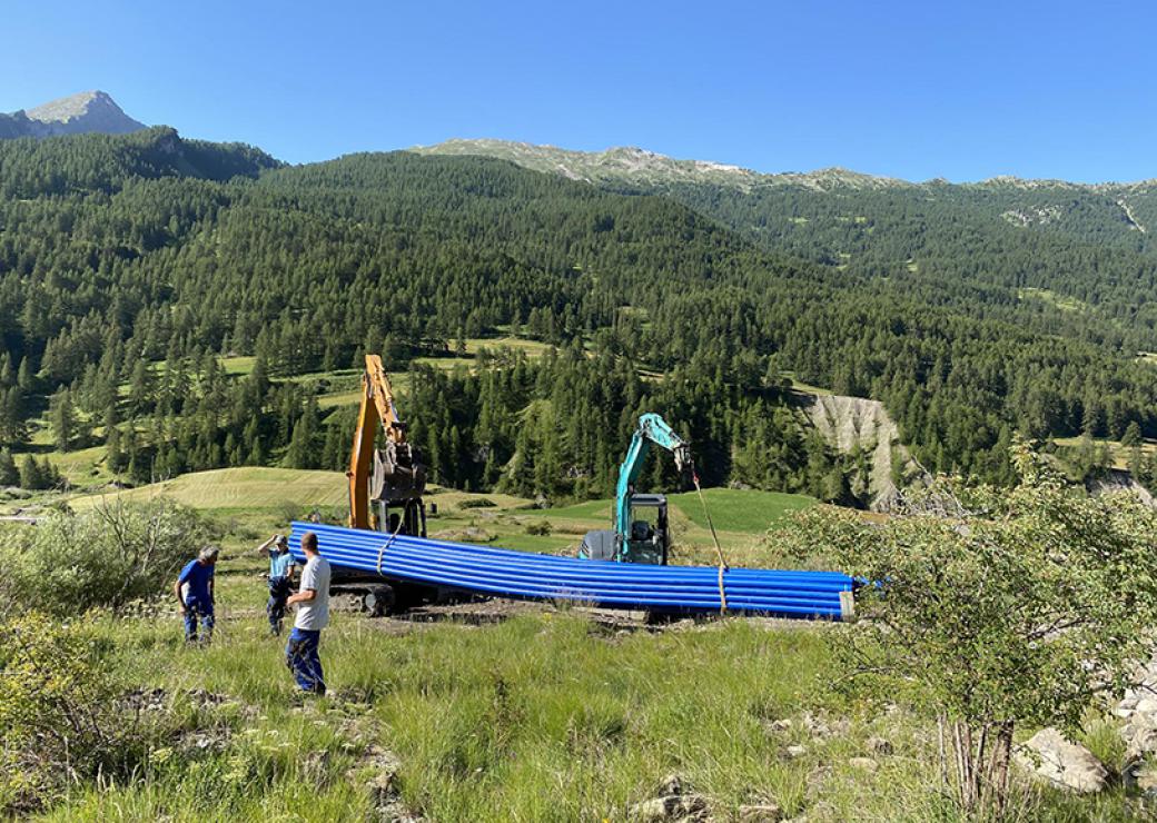 Sur des collines, deux tractopelles décharges un lot de tuyaux