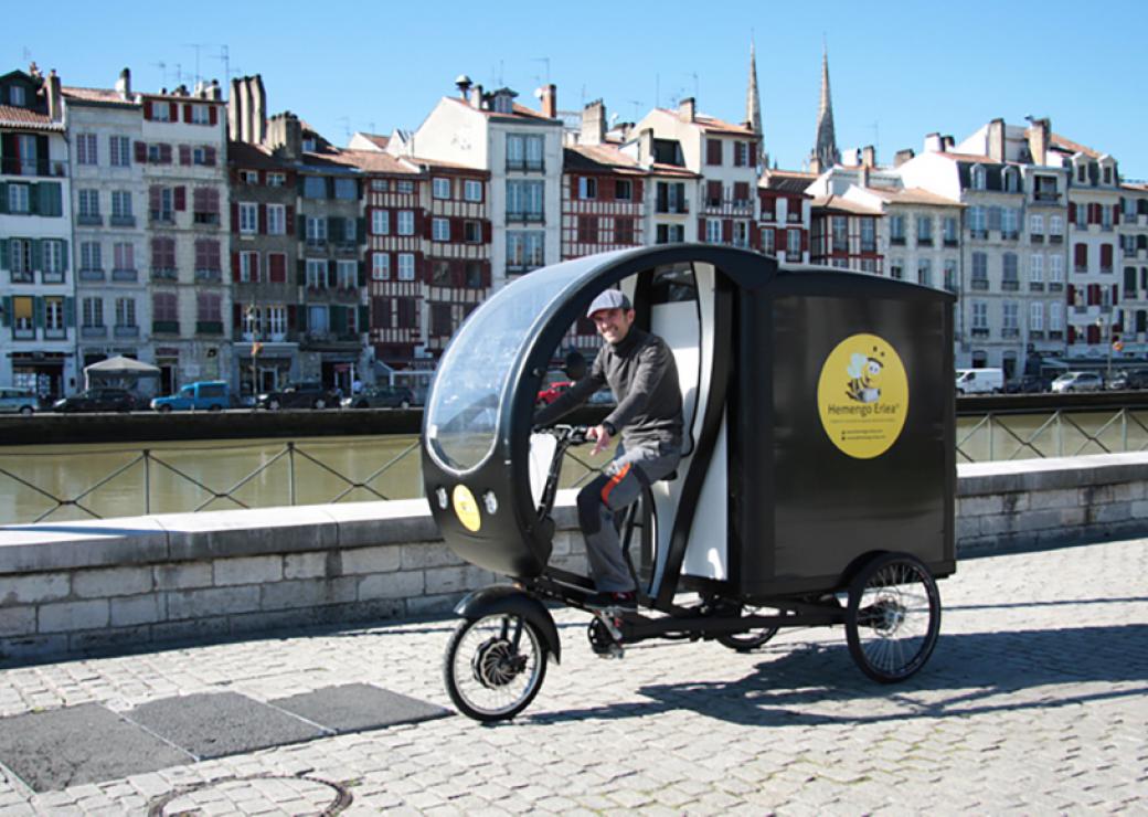 Plan large d'un vélo triporteur circulant sur les quais de Bayonne