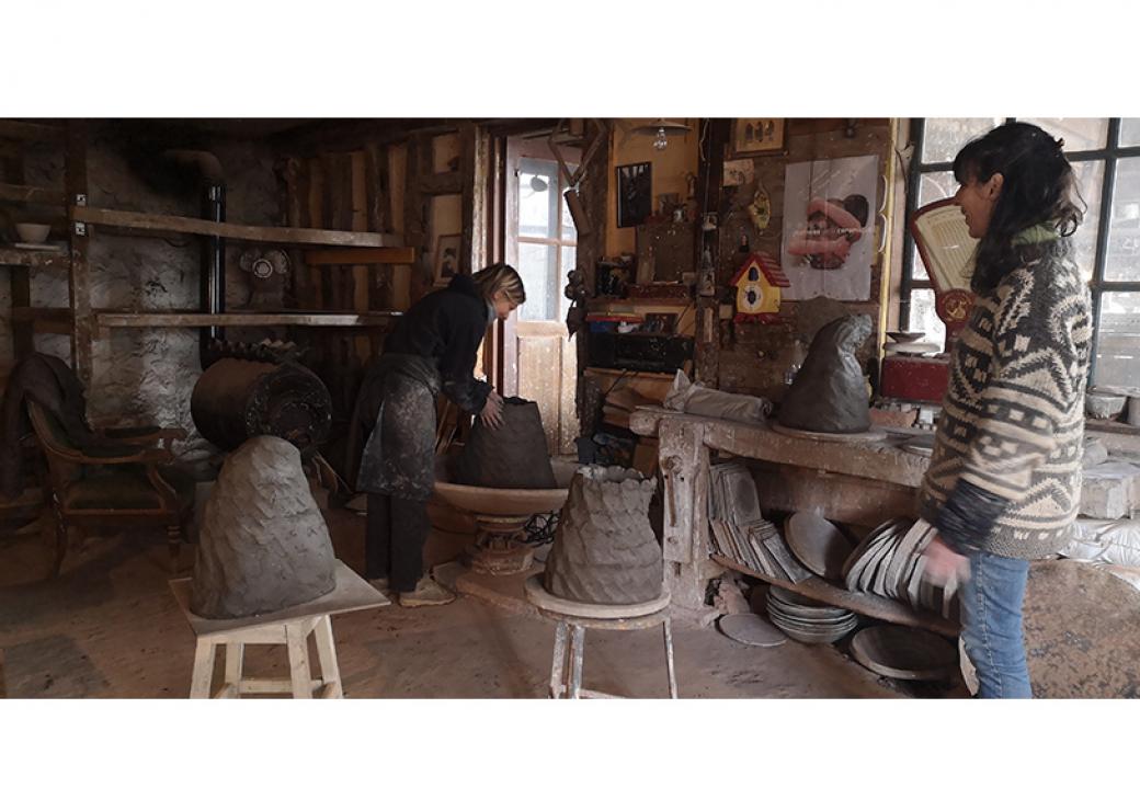 À l'intérieur d'un atelier, deux femmes travaillent à des sculptures de terre cure