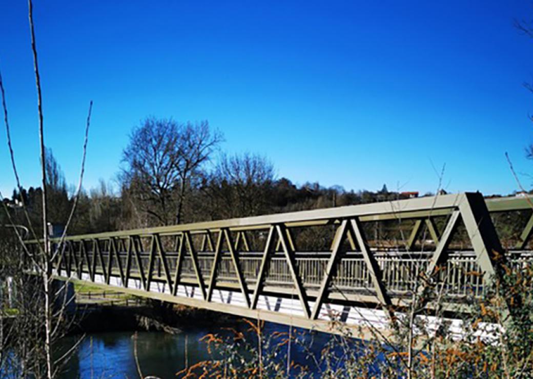 Vue oblique d'une passerelle métallique qui enjambe un cours d'eau