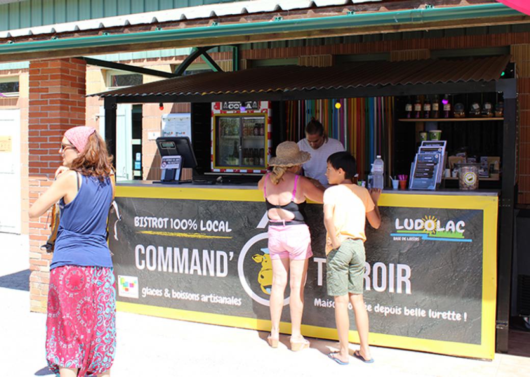 3 personnes attendent à un comptoir sur lequel on peut lire "Bistrot 100% local"