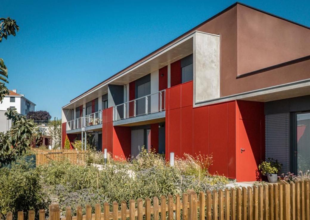 Vue d'un batiment d'un étage avec jardin et façade colorée en rouge