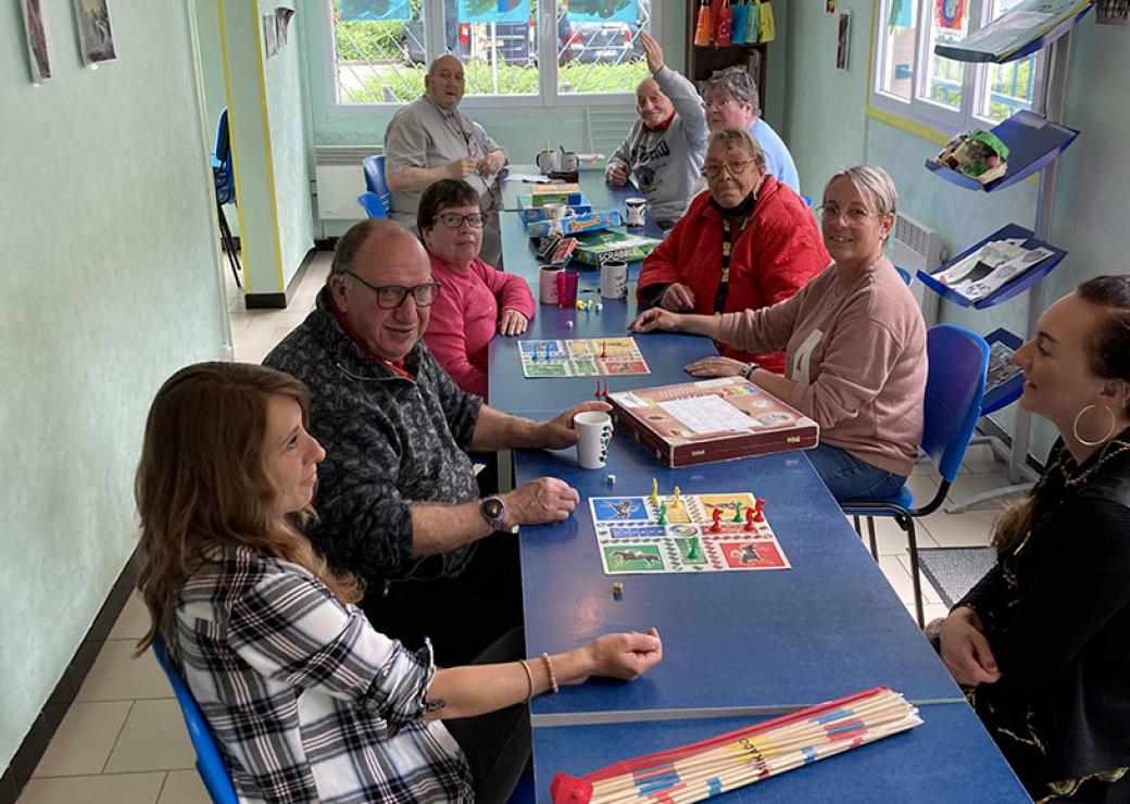 9 personnes se tiennent autour d'une table sur laquelle sont posés des jeux de société