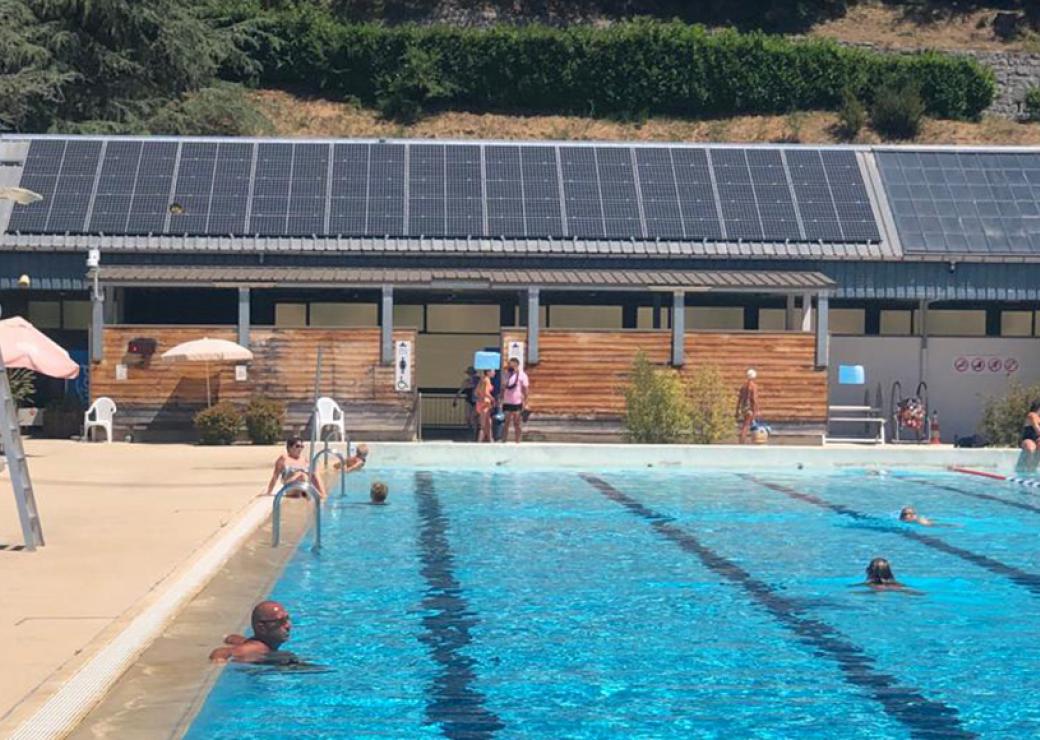 Une piscine de plein air, en arrière plan, le toit du bâtiment couvert de panneaux solaires