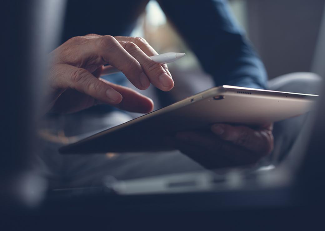 Zoom sur les mains d'un homme qui tient une tablette numérique