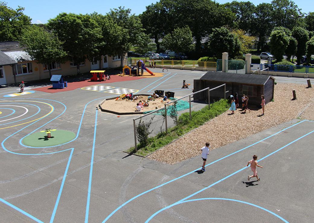 Vue d'en haut, une cour d'école dans laquelle une douzaine d'enfants jouent