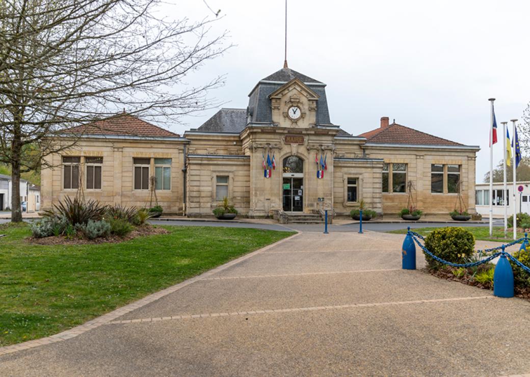 Un bâtiment neo classique aux toitures d'ardoise et de tuiles rouges sur le fronton on peut lire "mairie'