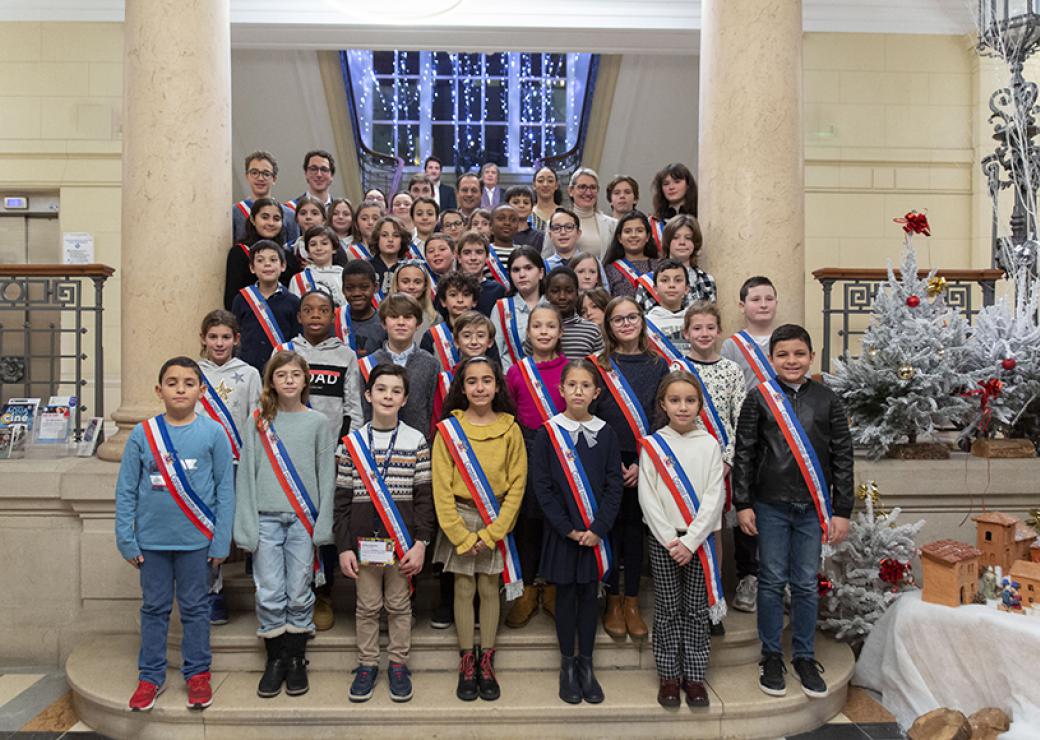 Sur les marches d'un escalier monumental, des enfants ceints d'une écharpe tricolore posent en groupe