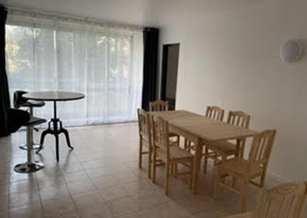 Une salle à manger éclairée par une baie vitrée et meublée d'une grande table et d'un mange-debout