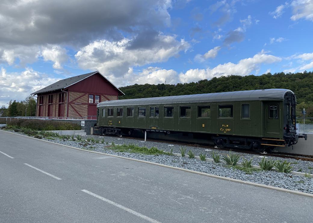 Sur le bord d'une route, un wagon de train ancien et une maison de briques