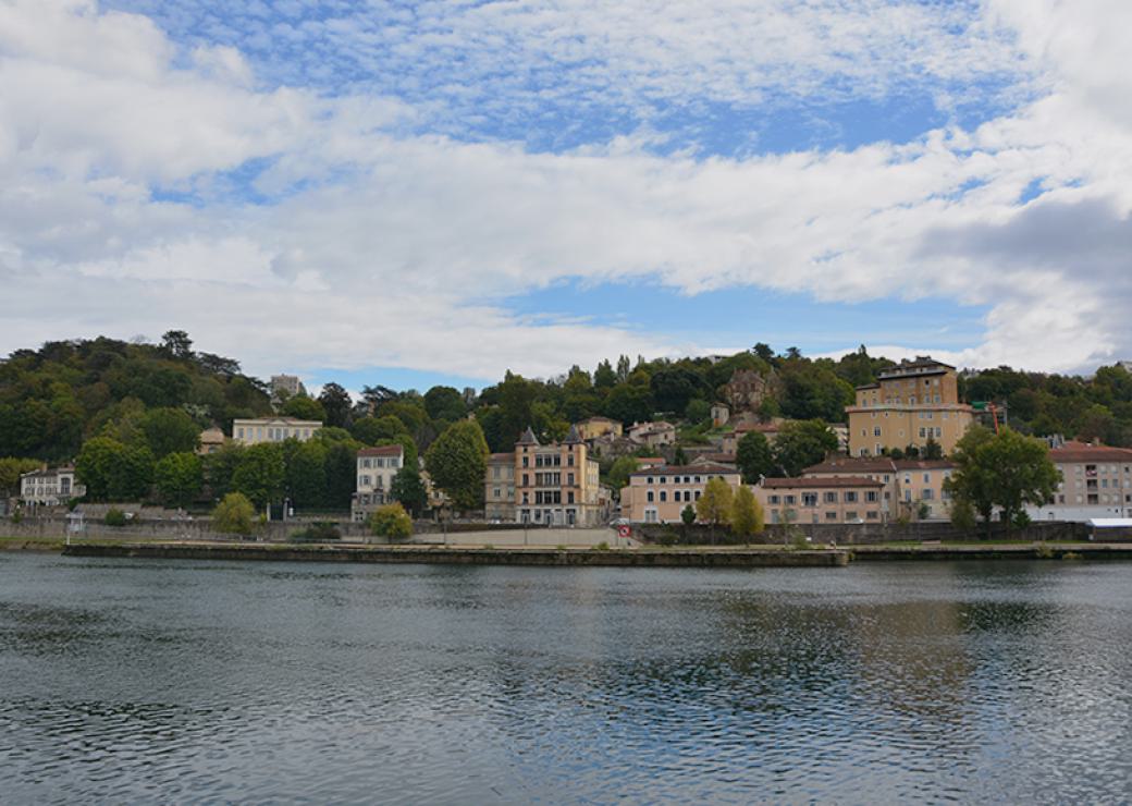 Photo d'une coline au pied de la quelle coule un fleuve. Sur la berge et les pentes, on voit des bâtiments d'habitation