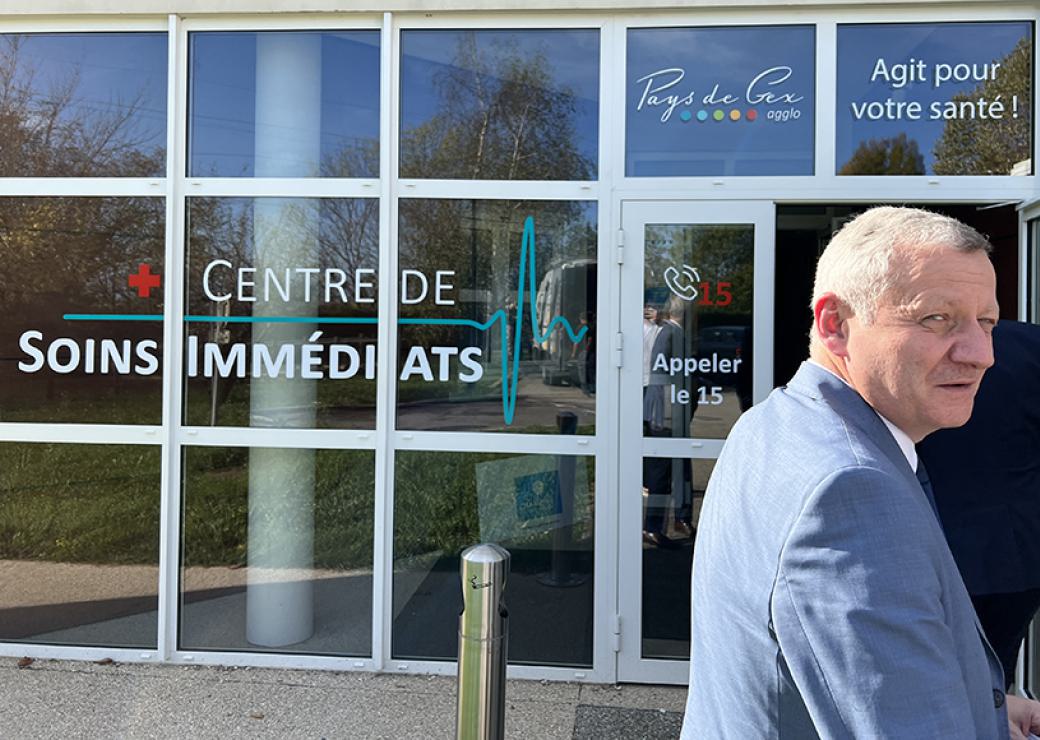 Un homme se tient devant une vitrine sur laquelle on peut lire : centre de soins immédiats Pays de Gex agit pour votre santé