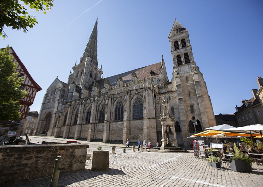 Une église gothique, une maison à colombages, une place pavée et de grands parasols de terrasses de cafés