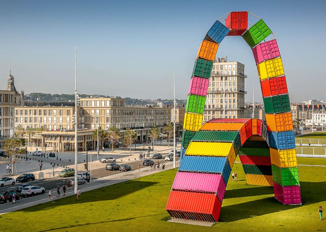 Sur une immense pelouse, deux arches géantes constituées de containers multicolores