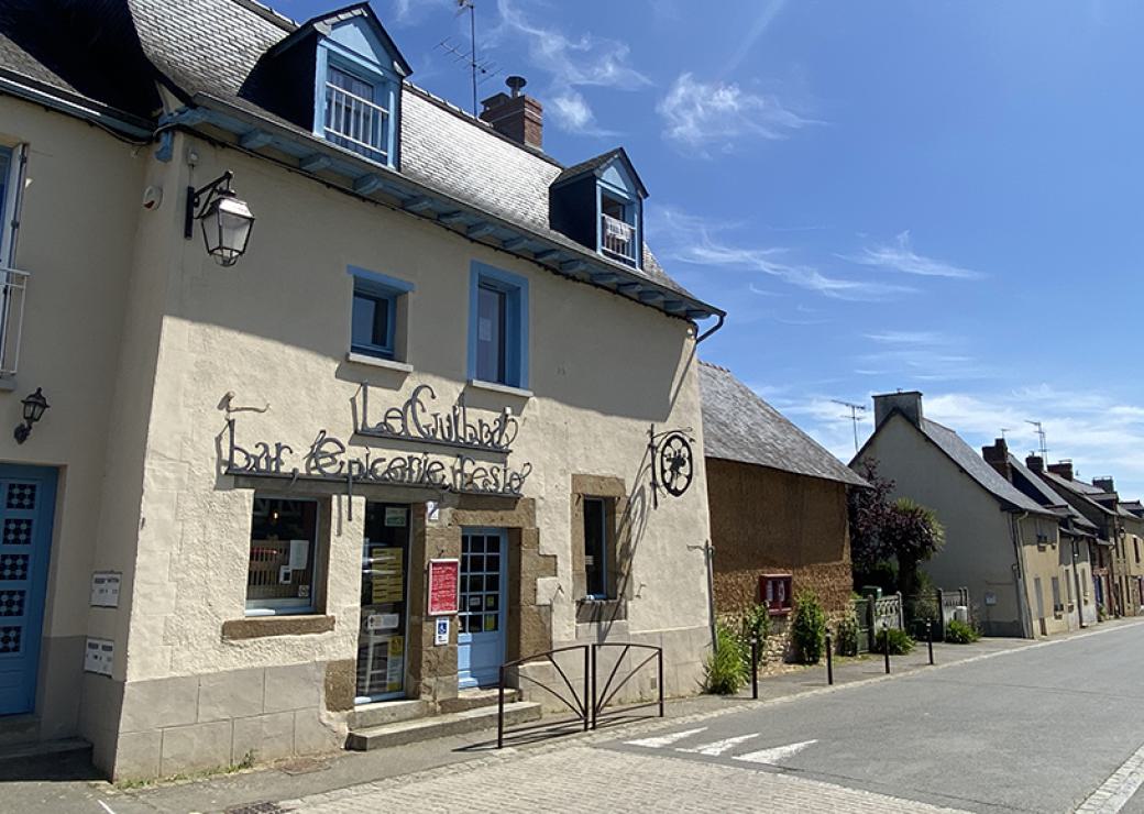 Façade d'une maison de village sur laquelle on peut lire "bar, épicerie, feste"