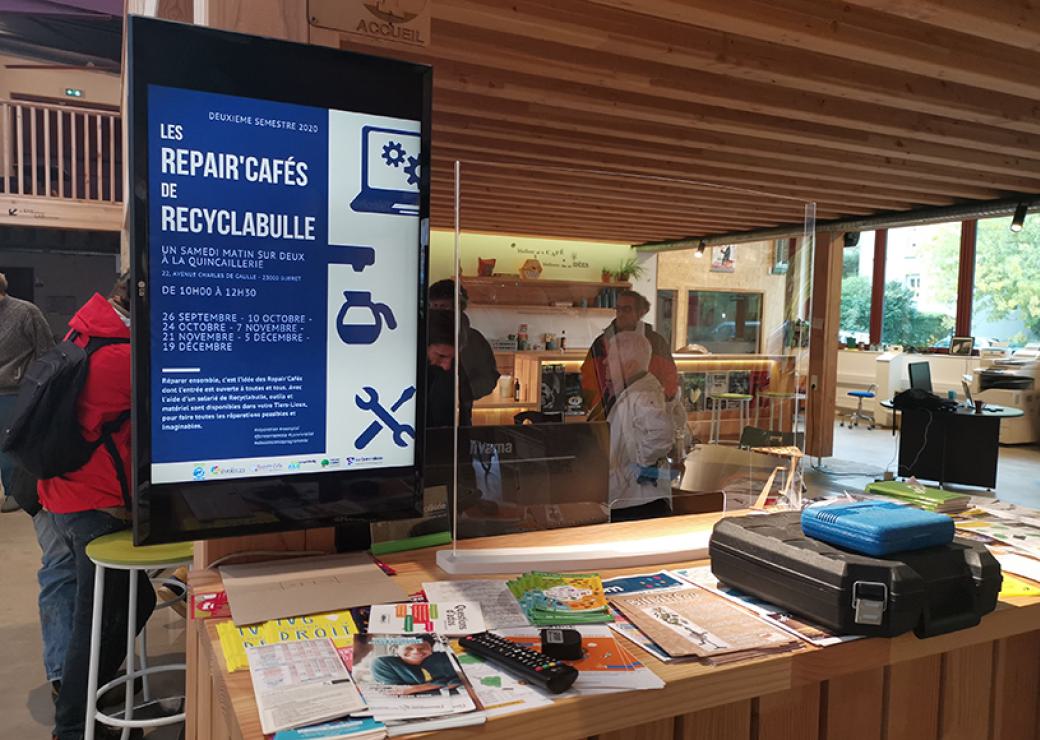 Dans une salle au plafond et murs couverts de bois, 4 personnes discutent debout