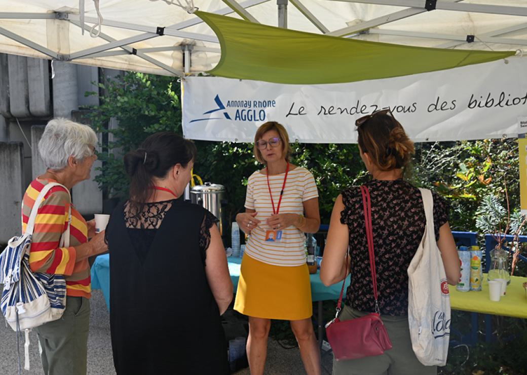 Quatre femmes discutent devant une table au dessus de laquelle on peut lire Annonay Rhone Agglo le rendez-vous des biblio