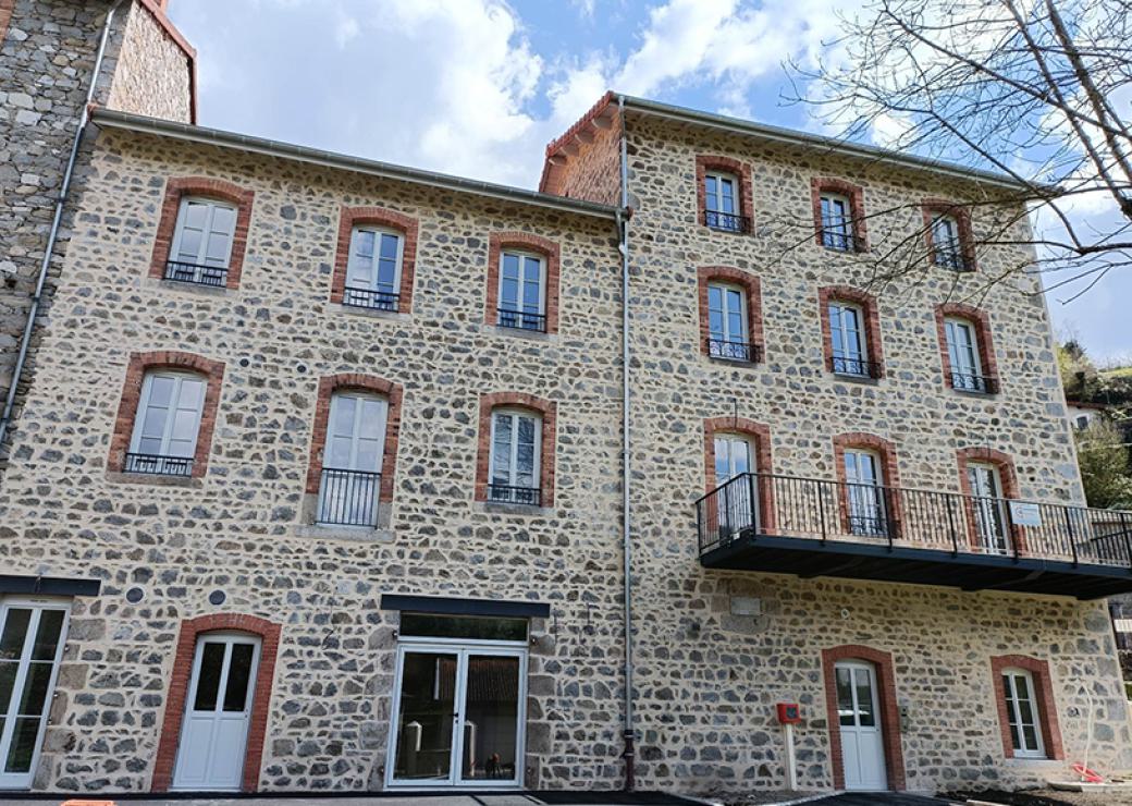 Façade d'une imposante maison de village, avec pierres apparentes