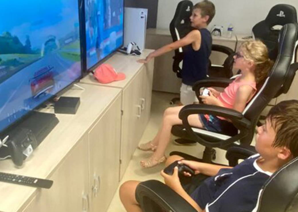 Trois enfants devant de grands écrans de jeux vidéos