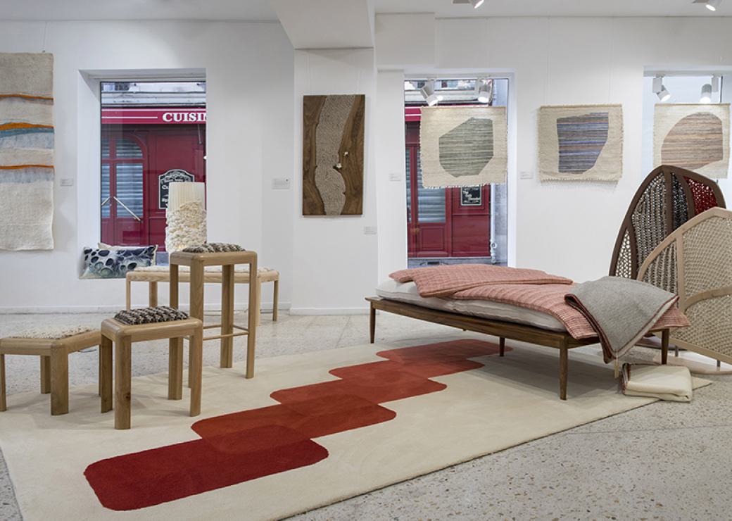 Showroom avec au sol un tapis, des couvertures pliées sur une banquette et des tentures aux murs