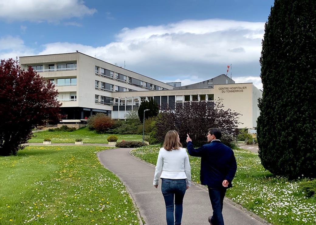 Deux personnes marchent sur un chemin entouré de pelouse, ils se dirigent vers un bâtiment moderne