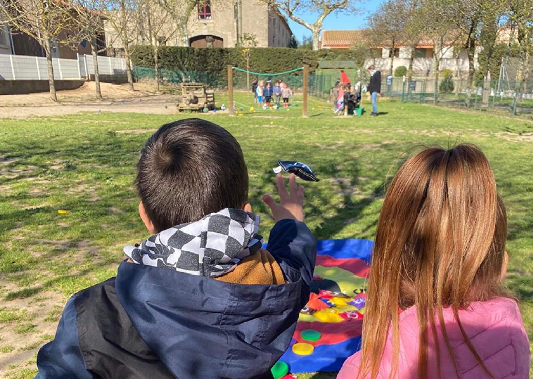 Deux enfants lancent des palets sur une cible étalée sur la pelouse