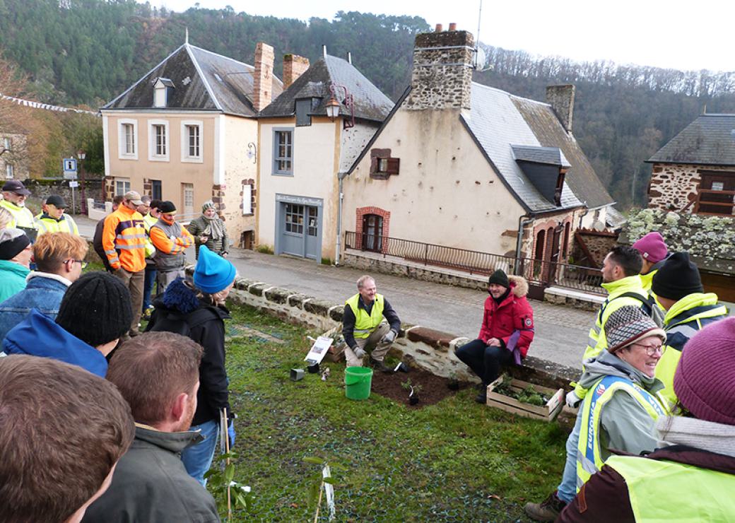 Un groupe de personnes regardent deux personnes qui plantent un végétal