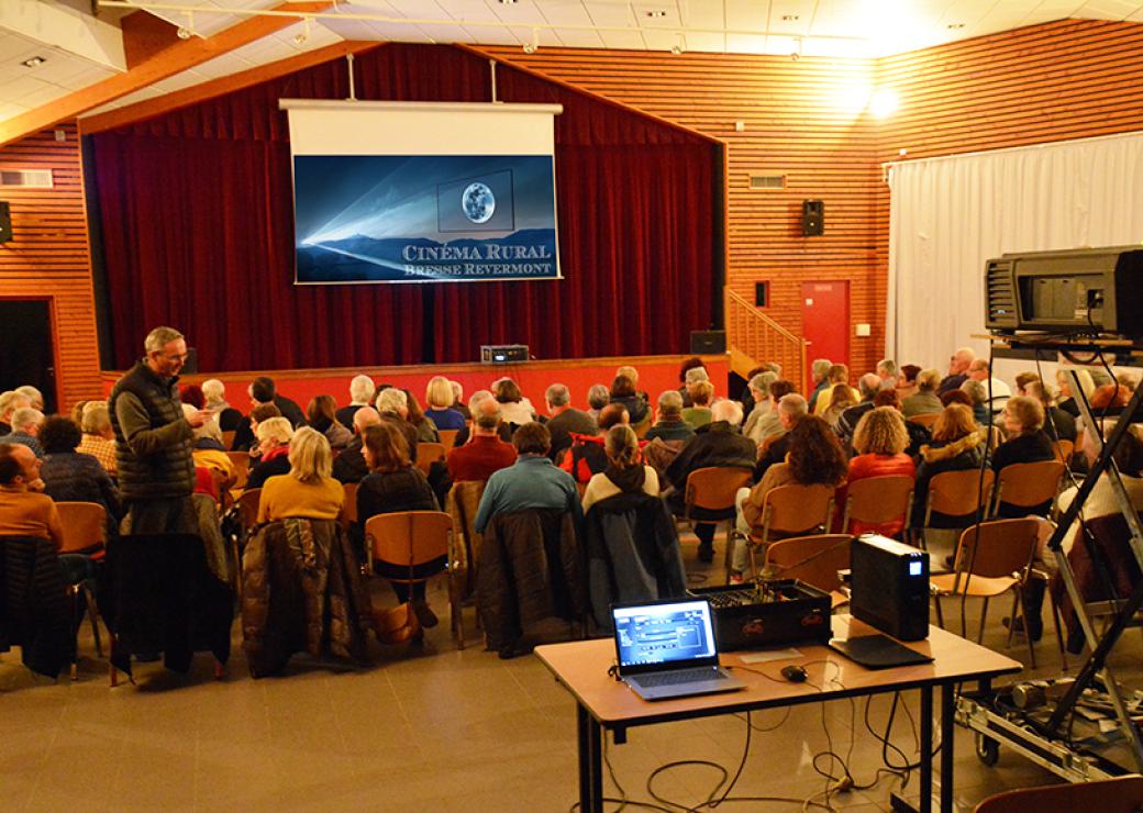 Des personnes assises devant un grand écran