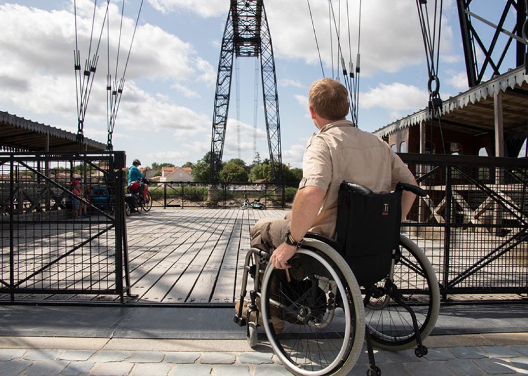 Une personne en fauteuil roulant s'engage sur un pont