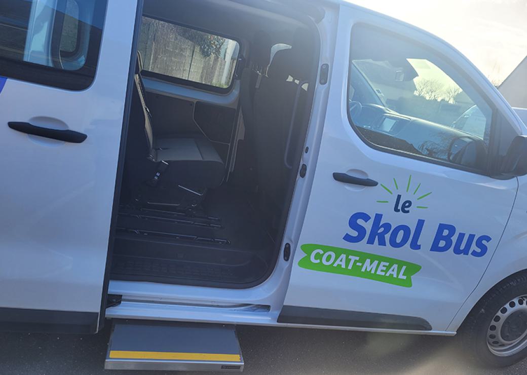 Petit bus blanc sur lequel on peut lire "le Skolbus Coat Meal"