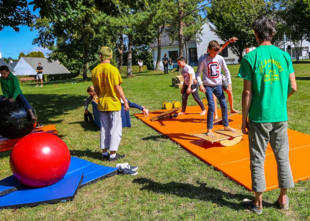 Sur une pelouse, des enfants sont engagés dans des jeux d'adresse et d'équilibre