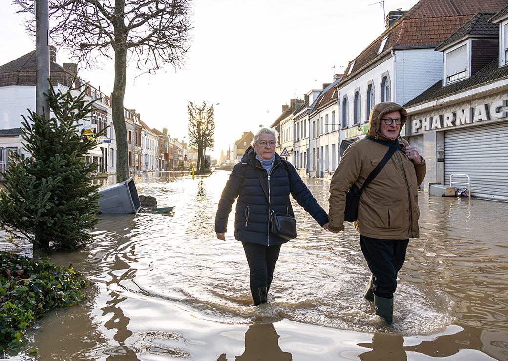 un couple marche dans une rue inondée