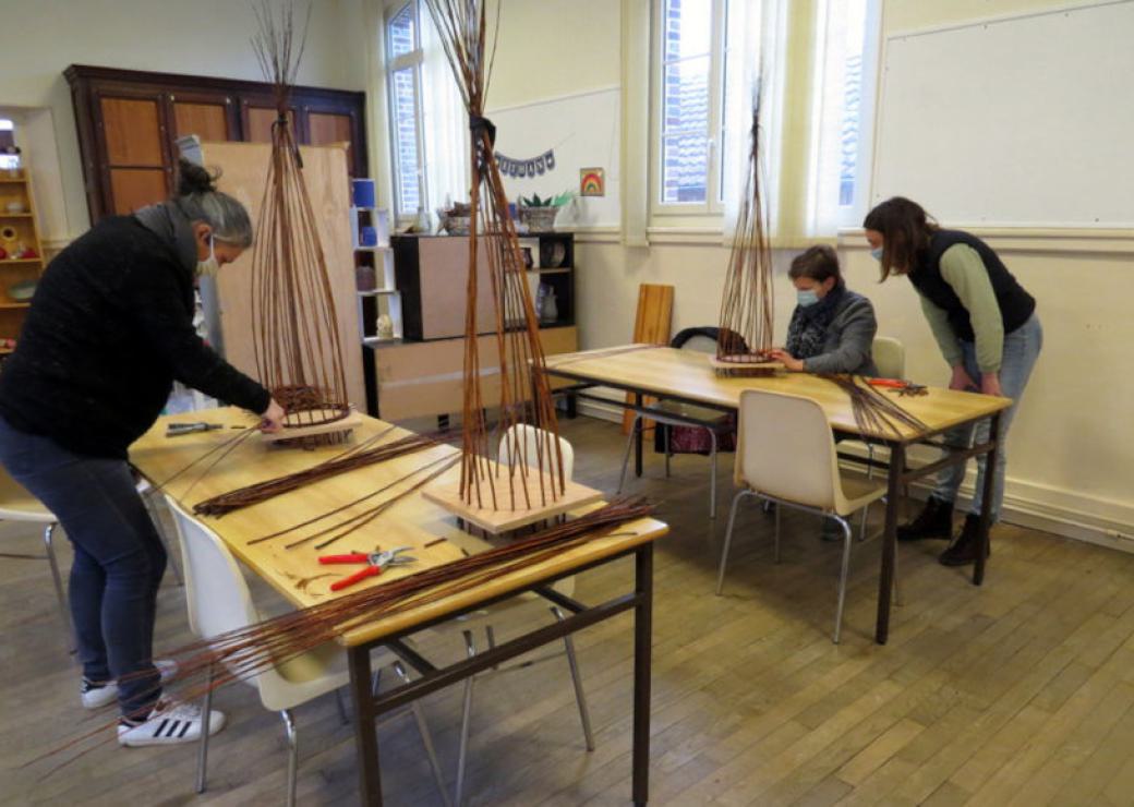 Trois personnes s'affairent sur des grandes tables