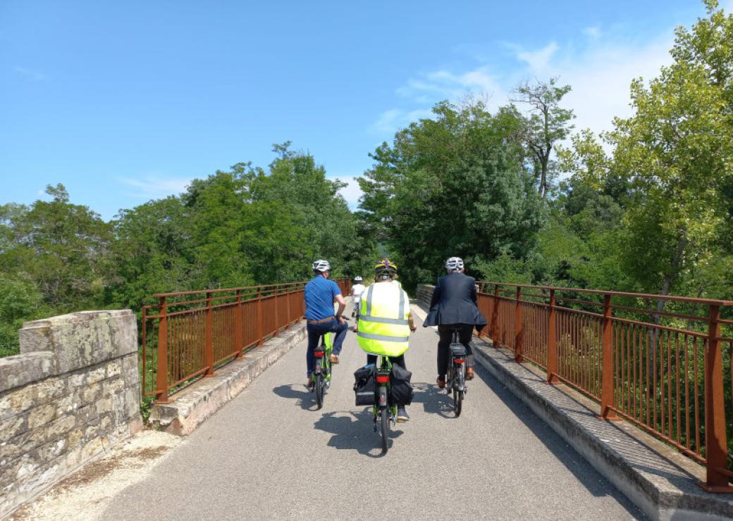 Trois personnes vue de dos circulent à vélo sur un pont