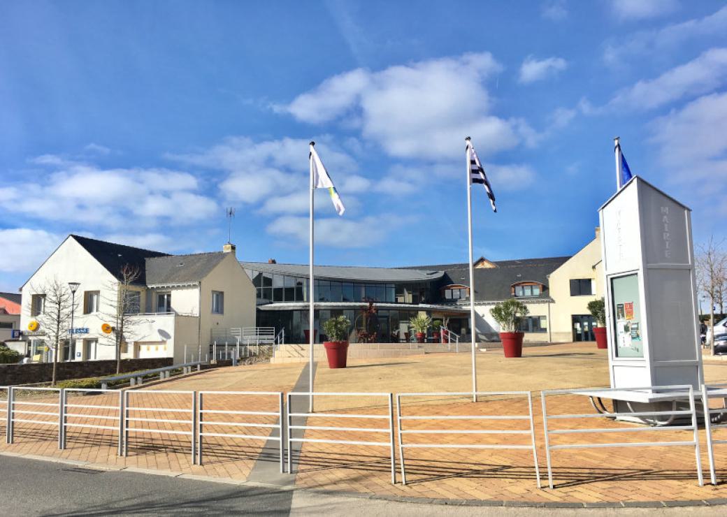 Un bâtiment moderne sur une large place plantée de drapeaux