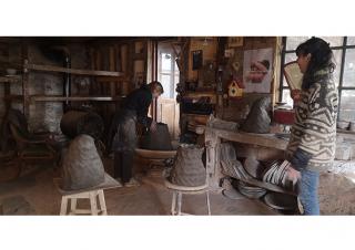 À l'intérieur d'un atelier, deux femmes travaillent à des sculptures de terre cure
