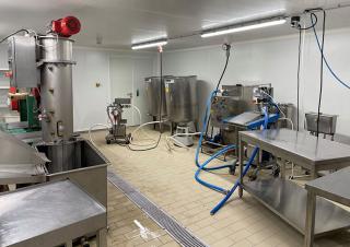Photo d'un labo de cuisine avec de grandes machines en inox, éclairé par deux néons