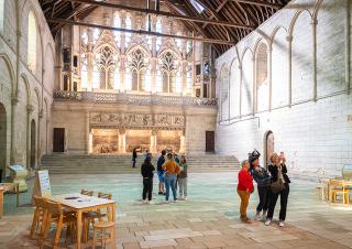 Dans une pièce très vaste, une dizaine de personnes photographient l'espace autour d'eux. Le mur du fond est une dentelle architecturale de fenêtres gothiques