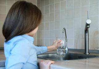 un enfant se sert un verre d'eau au robinet 
