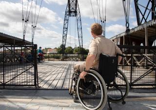 Une personne en fauteuil roulant s'engage sur un pont
