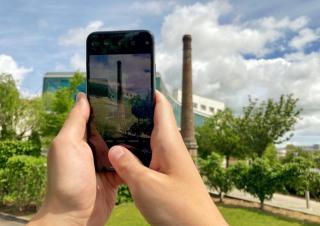 Un smartphone dans les mains d'une personne qui prend en photo une haute cheminée en briques